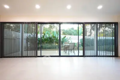 Spacious living room with sliding glass doors opening to a lush garden patio, perfect for indoor-outdoor living.