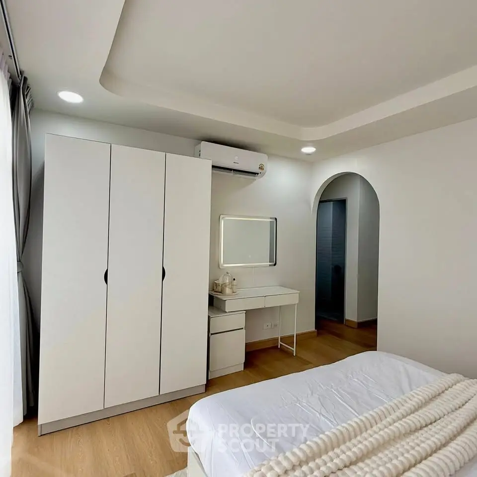 Modern bedroom with sleek design, featuring a wardrobe, vanity, and cozy bed in a bright space.