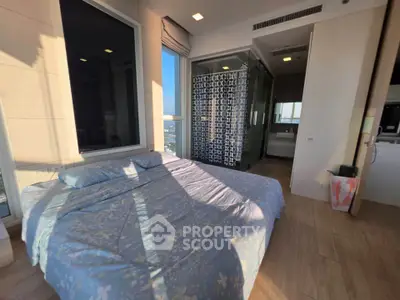 Spacious bedroom with large windows and ensuite bathroom in modern apartment.