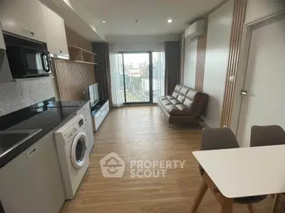 Modern open-layout living room with kitchen, featuring a washing machine and city view.