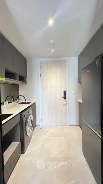 Modern kitchen with sleek cabinetry, washing machine, and fridge in a compact layout.