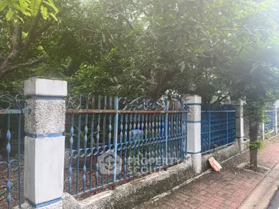 Charming garden view with classic blue wrought iron fence and lush greenery.