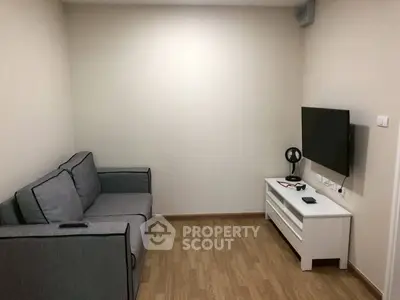 Cozy living room with modern sofa and wall-mounted TV, perfect for relaxation.