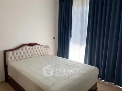 Spacious bedroom with elegant bed and large window with blue curtains.