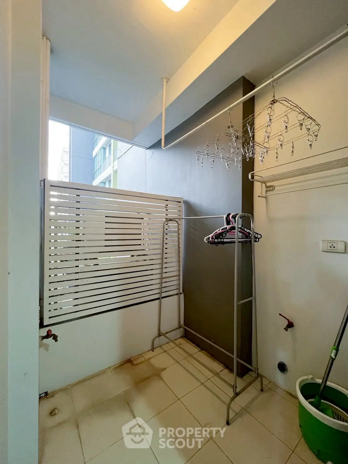 Compact laundry area with drying rack and utility sink in modern apartment.