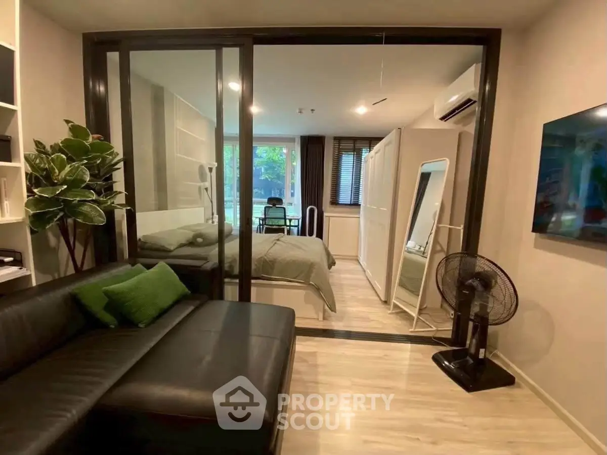 Modern studio apartment with glass partition, cozy living area, and stylish decor.