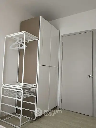 Modern storage area with sleek cabinet and clothes rack in minimalist design.