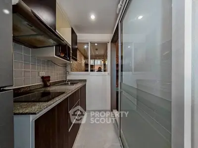 Modern kitchen with sleek dark cabinets and granite countertops in a compact layout.