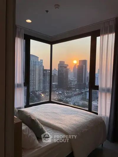 Stunning bedroom with panoramic city view and sunset, featuring floor-to-ceiling windows.