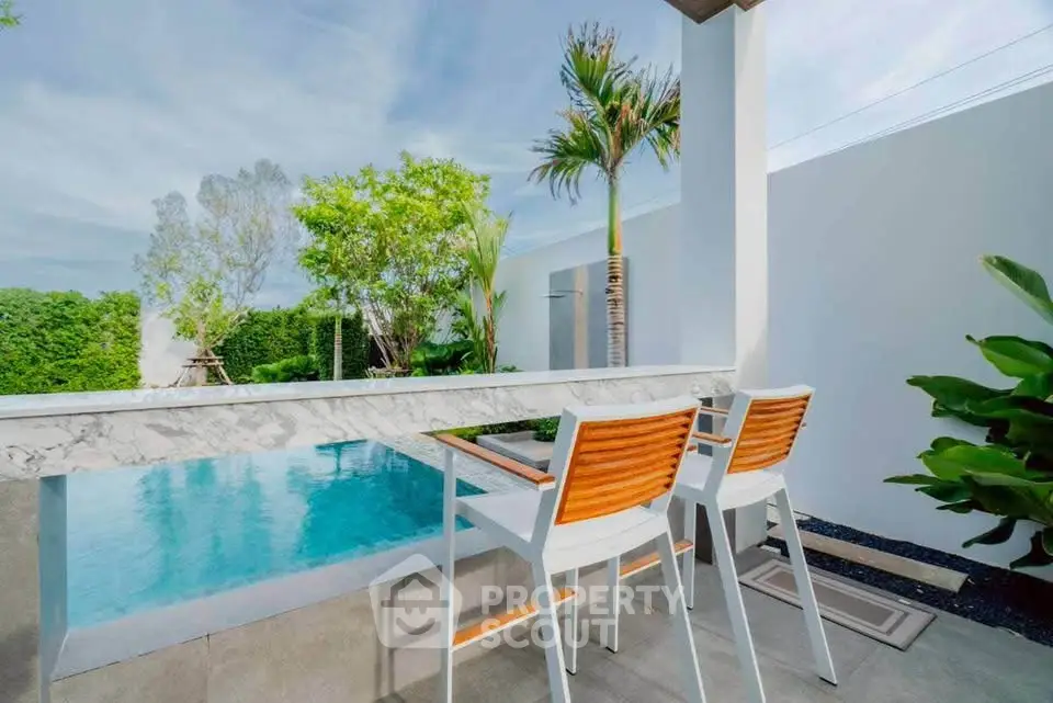 Luxurious outdoor pool area with modern seating and lush greenery, perfect for relaxation and entertainment.