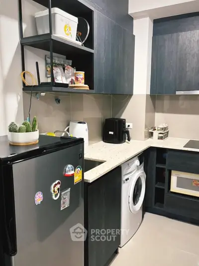 Modern kitchen with sleek cabinets, washing machine, and compact fridge