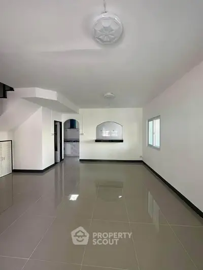 Spacious open-plan living area with modern tile flooring and ample natural light.