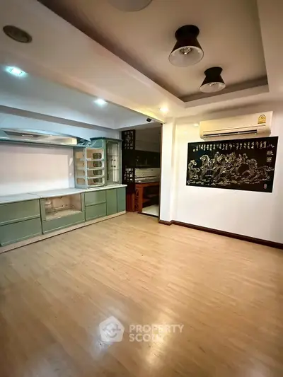 Spacious living room with wooden flooring and modern lighting, ideal for cozy gatherings.