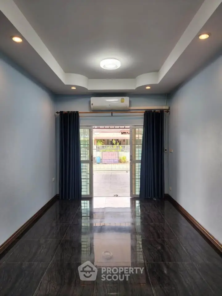 Spacious living room with glossy floor and modern ceiling lights, featuring large windows and blue curtains.