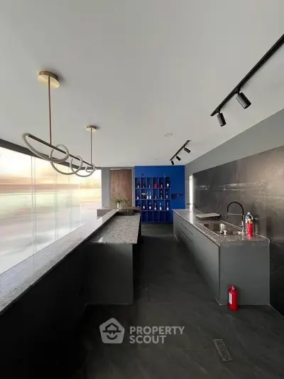 Modern kitchen with sleek design, featuring a long countertop and stylish lighting fixtures.