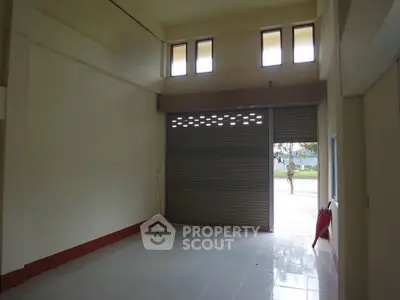 Spacious commercial space with high ceilings and large shutter door.