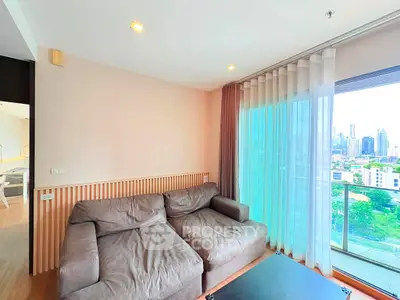 Spacious living room with large windows and city view, featuring a comfortable sofa and modern decor.