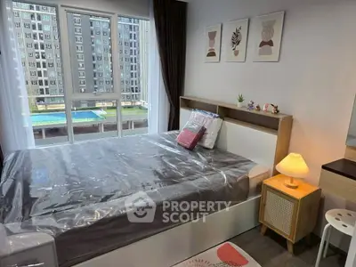 Modern bedroom with large window and stylish decor in urban apartment.