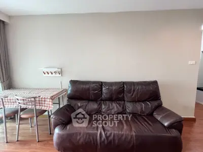 Cozy living room with leather sofa and dining area, perfect for relaxation and entertaining.