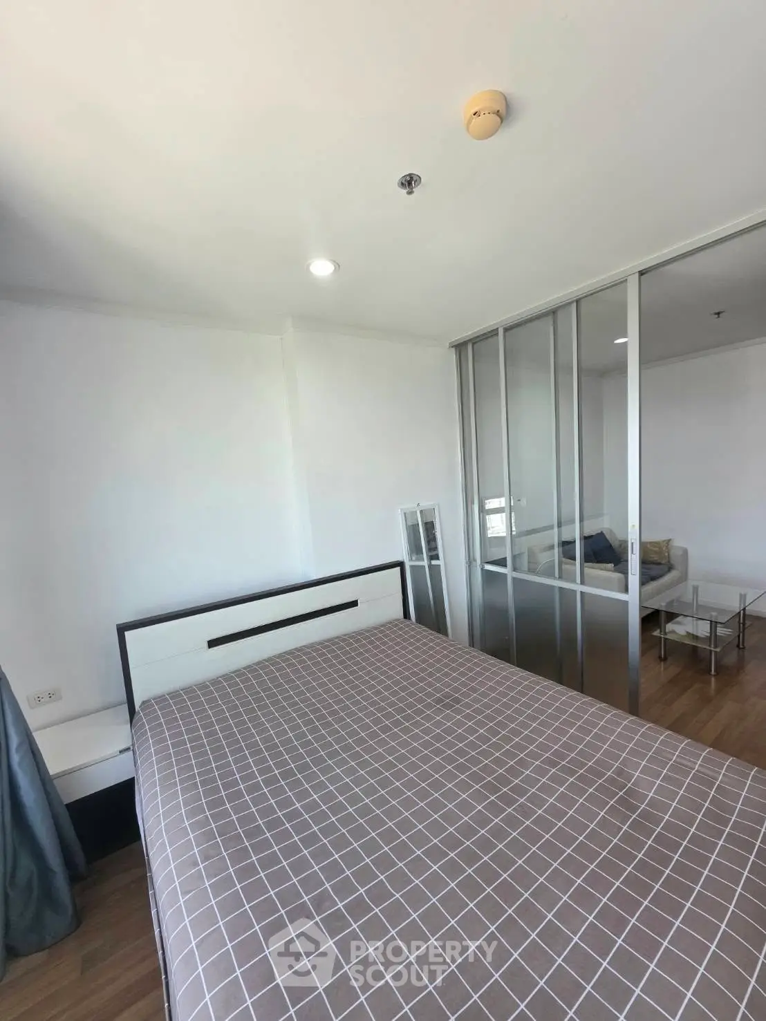 Modern bedroom with sliding glass doors leading to a cozy living area, featuring stylish decor and ample natural light.