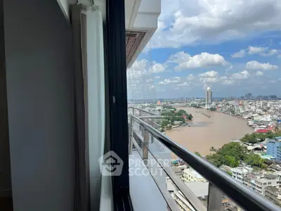 Stunning high-rise balcony view overlooking a vibrant cityscape and river under a clear blue sky.
