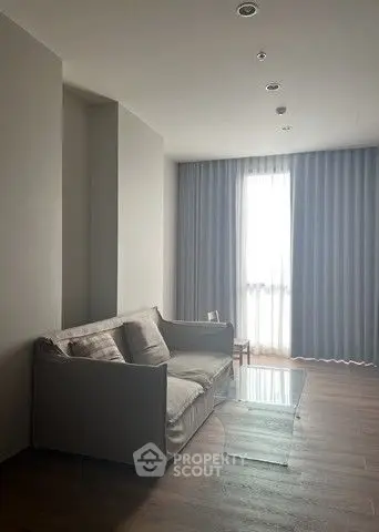 Cozy living room with modern sofa and floor-to-ceiling window curtains.