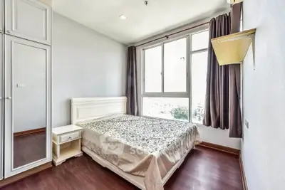 Bright and cozy bedroom with large window and elegant furnishings in modern apartment.
