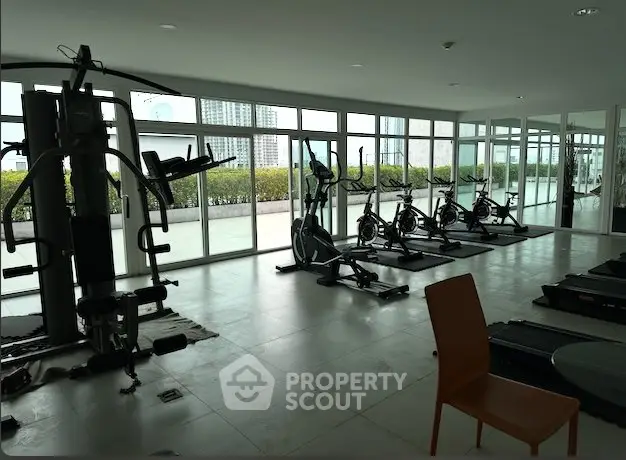 Spacious gym with modern equipment and panoramic city views in luxury residential building.