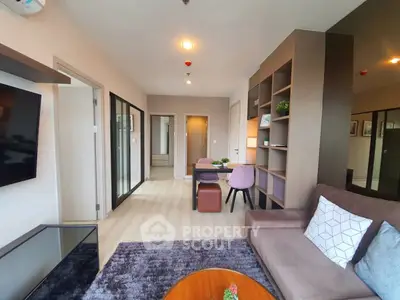 Modern living room with stylish decor and open layout, featuring a cozy sofa and sleek shelving.