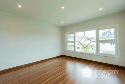 Spacious empty room with large windows and wooden flooring, perfect for customization.