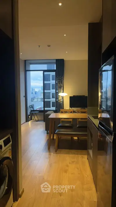 Modern apartment interior with open kitchen and living area, featuring wooden flooring and city view.