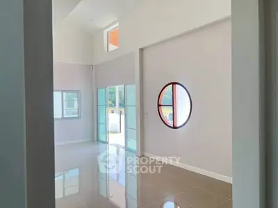 Spacious modern living room with high ceilings and unique circular window design.
