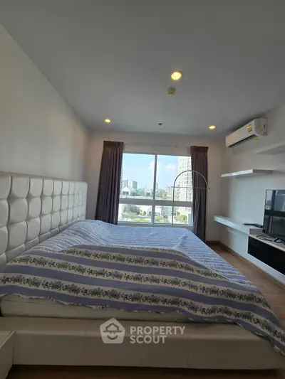 Spacious bedroom with city view, modern furnishings, and natural light.