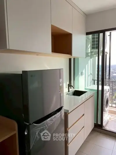 Modern compact kitchen with balcony view and appliances