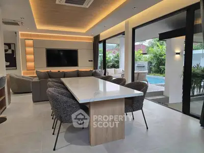 Luxurious open-plan living room with pool view, featuring modern furniture and elegant lighting.