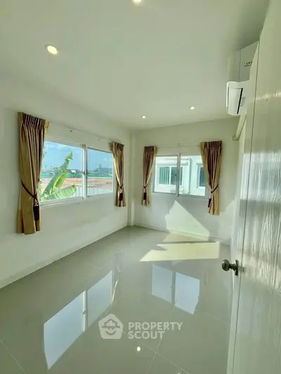Bright and airy room with large windows and glossy tiled floor, perfect for a cozy living space.