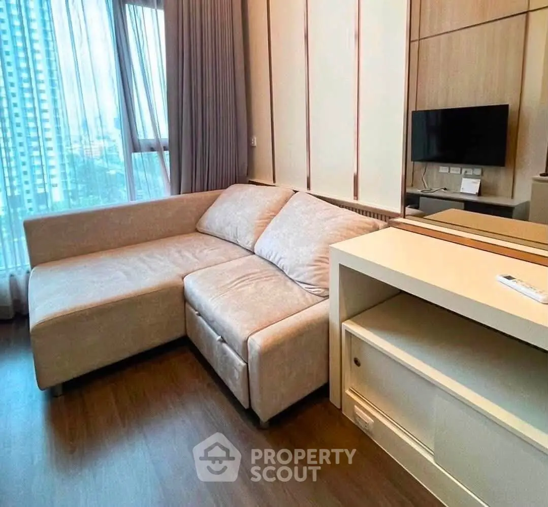 Modern living room with cozy sectional sofa and sleek TV setup in high-rise apartment.