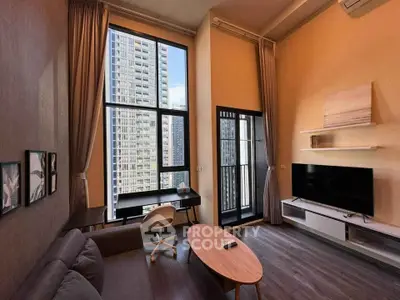 Modern living room with high ceilings and city view, featuring stylish furniture and large windows.