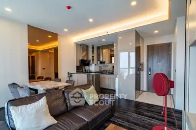 Modern open-plan living room with sleek kitchen and dining area, featuring stylish decor and ample lighting.