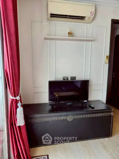 Chic living room corner with TV, air conditioning, and elegant red curtains.