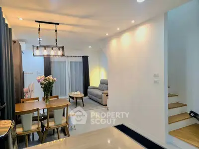 Modern open-plan living and dining area with stylish lighting and cozy seating.