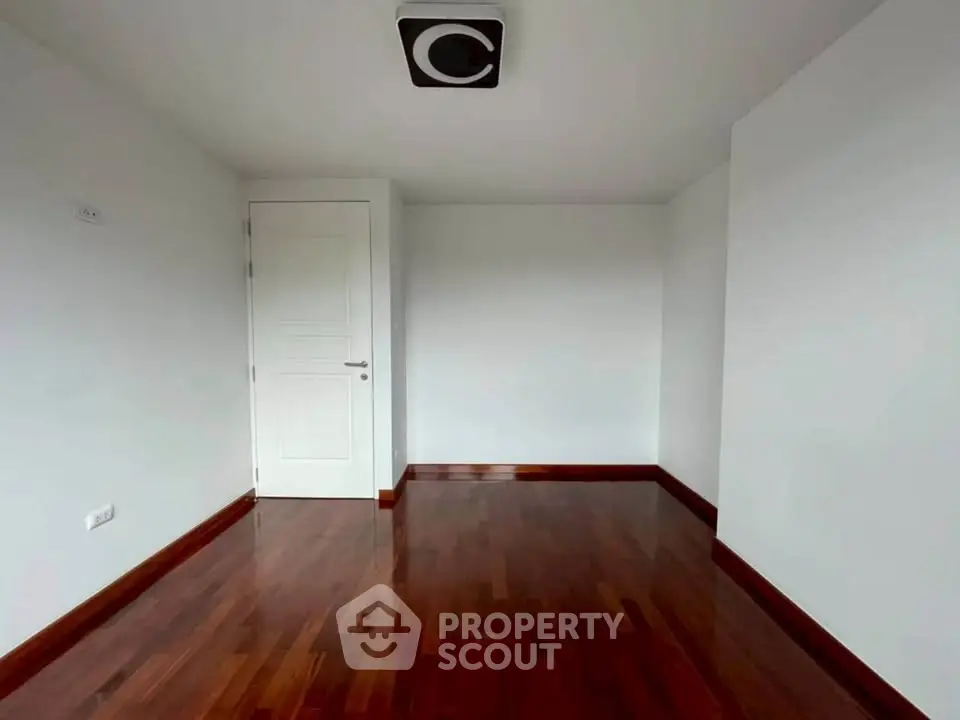Spacious empty room with polished wooden floors and white walls, ideal for customization.