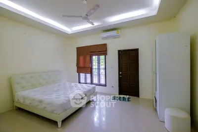 Spacious bedroom with modern decor and large window for natural light.