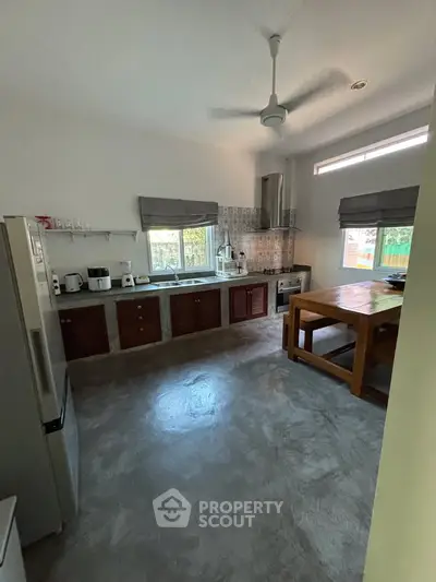 Spacious kitchen with modern appliances and open layout, featuring a large wooden dining table.