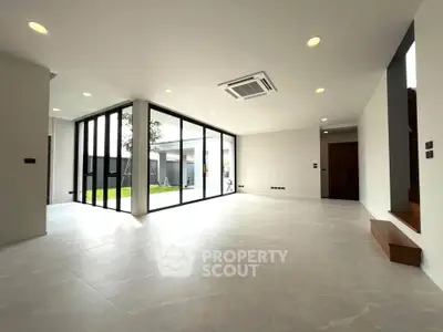 Spacious modern living room with large windows and garden view, perfect for family gatherings.
