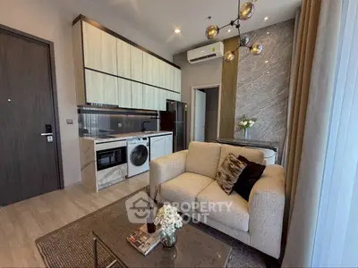 Modern living room with open kitchen, featuring stylish decor and appliances.