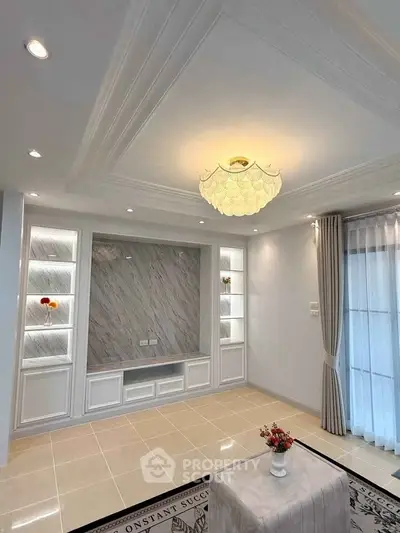 Elegant living room with modern ceiling design and natural light, featuring built-in shelves and stylish decor.
