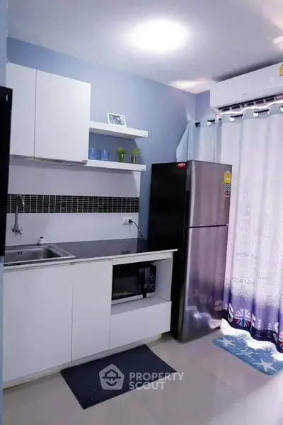 Modern kitchen with sleek cabinetry, stainless steel appliances, and stylish backsplash in a cozy apartment.