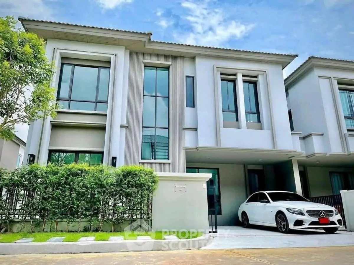 Modern two-story house with sleek design and luxury car in driveway