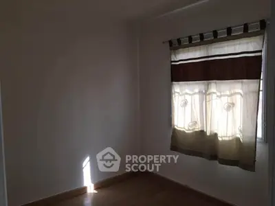Cozy room with wooden flooring and window curtains, perfect for a small bedroom or study.